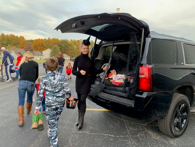 Woman handing out candy to kids trunk or treating