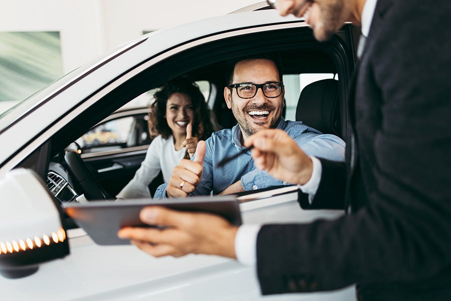 Man smiling through drivers side window at salesman